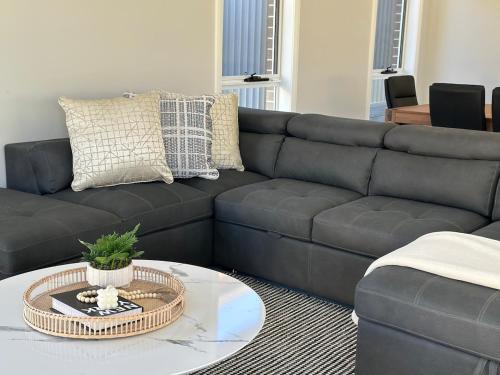 a living room with a black couch and a coffee table at Cozy & Spacious 5BR Family Home with Free On-Site Parking in Pendle Hills