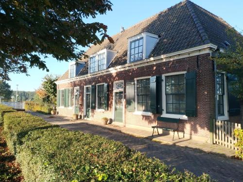 an old brick building with a bench in front of it at Bed & Breakfast [H]eerlijk! in De Kwakel