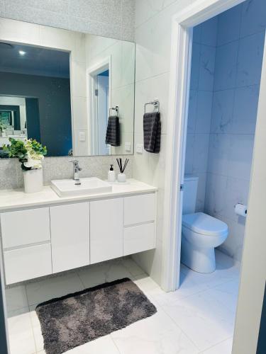 a white bathroom with a sink and a toilet at Cozy & Spacious 5BR Family Home with Free On-Site Parking in Pendle Hills