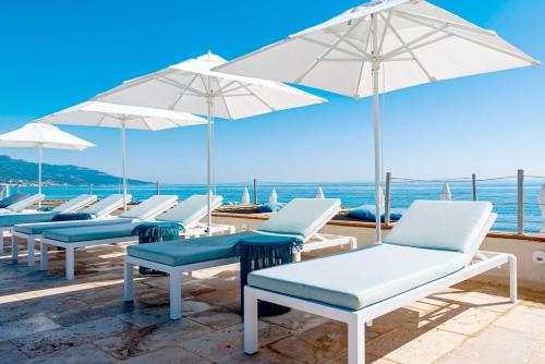 a row of chairs and umbrellas on a beach at Hôtel Pineto in Biguglia