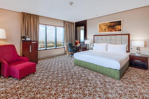 a hotel room with a bed and a red chair at Holiday Inn Cochin by IHG in Cochin