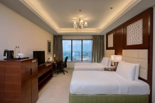 a hotel room with two beds and a desk with a computer at Holiday Inn Cochin by IHG in Cochin