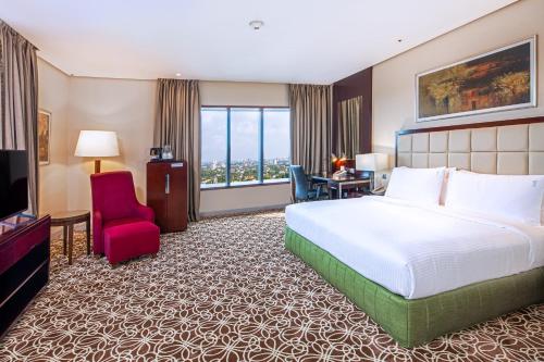a hotel room with a large bed and a red chair at Holiday Inn Cochin by IHG in Cochin