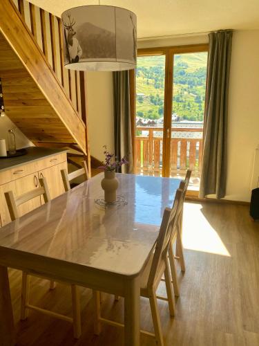 une table de salle à manger avec des chaises et une grande fenêtre dans l'établissement Appartement Duplex 6 ou 7 personnes dans chalet à 250 m des pistes, à Albiez-Montrond