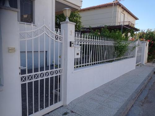 a white fence with a gate in front of a house at Aegean Touch Beach House in Artemida