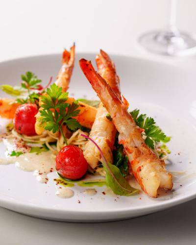 a white plate of food with shrimp and vegetables at Zendaya Resort Beach Sport & Spa in Búzios