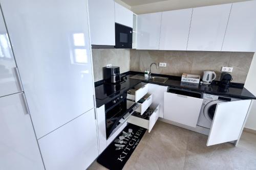 a kitchen with white cabinets and a washer and dryer at Apartamentos Golfinho Dourado in Santa Maria