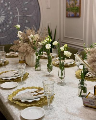 a table with plates and vases with flowers on it at Deutsch Hostel Osh in Osh