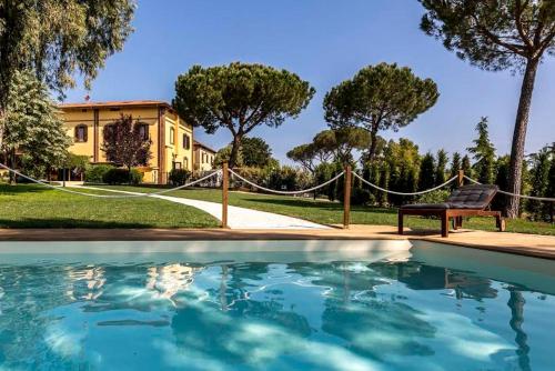 una piscina frente a una casa con un banco en Boma Countryhouse, en Casale Bufalotta