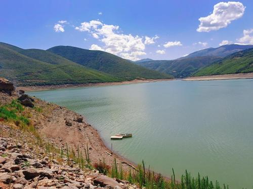 a boat in a large body of water with mountains at SuperPanorama GuestHouse in Kukës