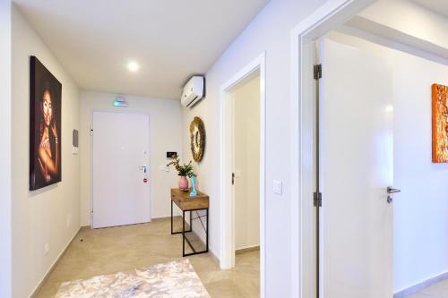 a hallway with white walls and a white door and a table at Apartamentos Golfinho Dourado in Santa Maria