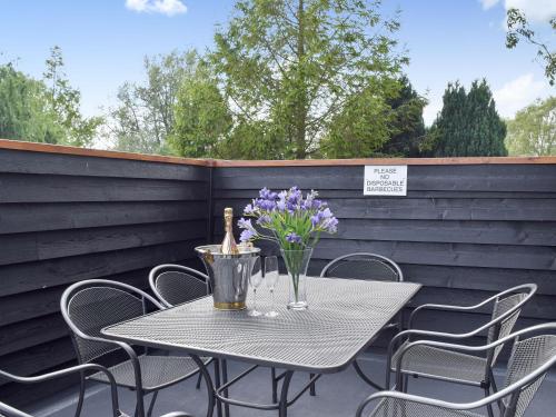 a table and chairs on a patio with purple flowers at Derby's Loft in Beccles