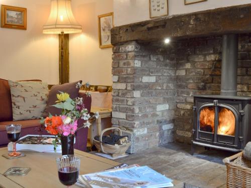 a living room with a fireplace and a table with flowers at Henley Bridge Holiday Cottage in Ashburnham