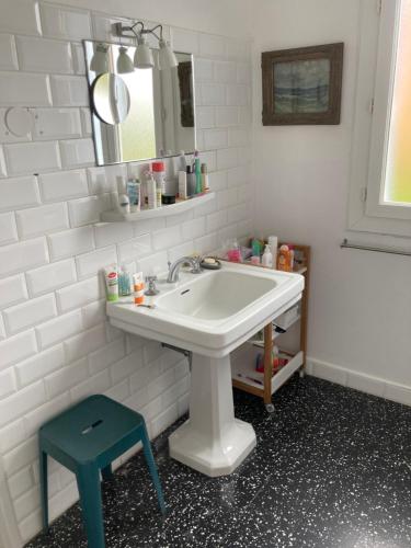 La salle de bains est pourvue d'un lavabo blanc et d'un tabouret bleu. dans l'établissement Komfortables Haus mit zwei Terrassen, à Collioure