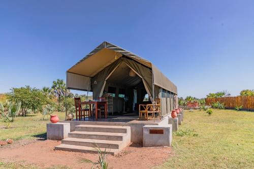 una tenda con sedie e tavoli in un campo di Muzanga Eco Guesthouse a Mfuwe