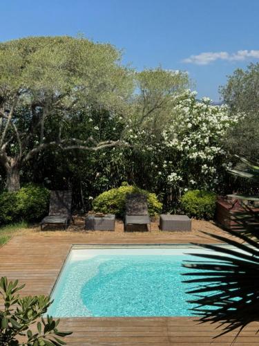 a swimming pool with two chairs and trees at Appartement en Rez de Villa in Porto-Vecchio