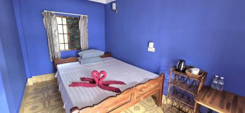 a bedroom with a bed with a red ribbon on it at Khmer House Guesthouse in Kep
