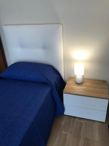 a bed with a blue blanket and a nightstand with a lamp at Residenza delle Rose in Lamezia Terme