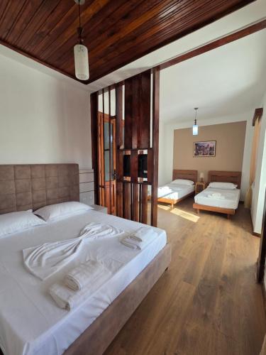 a bedroom with a large white bed and wooden floors at Antique House Muradie in Vlorë