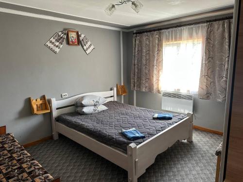 une chambre avec un lit avec des oreillers bleus et une fenêtre dans l'établissement Родинна оселя, à Slavsko