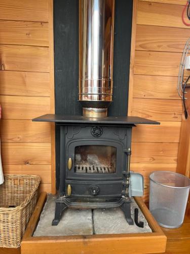 a black stove in a room with a wooden wall at Black Bridge Cabin in Lyonshall