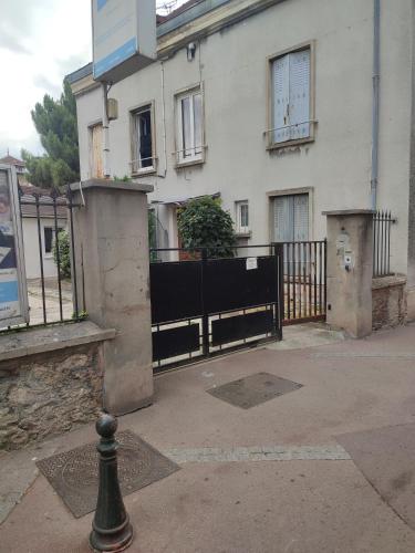 a white building with a black fence and a house at Le Studio de Savigny in Savigny-sur-Orge