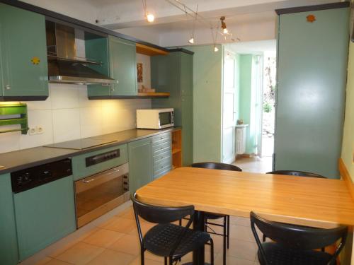 a kitchen with green cabinets and a wooden table with chairs at " Le cottage " in Mouans-Sartoux