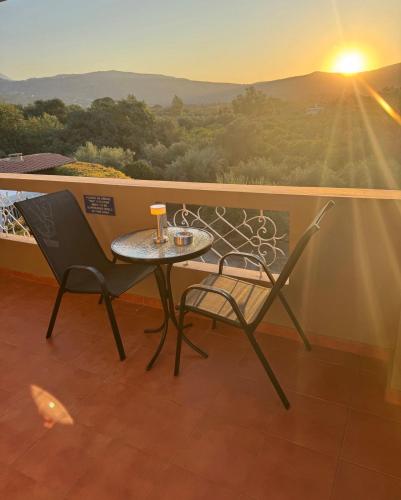a table and chairs on a balcony with the sunset at Villa Clio, with Mountain view in Arménoi
