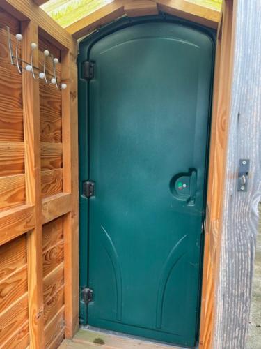 a green door in a room with wooden cabinets at Black Bridge Cabin in Lyonshall