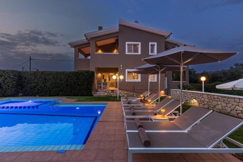 a row of lounge chairs next to a swimming pool at Villa Clio, with Mountain view in Arménoi