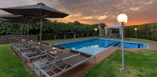 a pool with tables and umbrellas next to at Villa Clio, with Mountain view in Arménoi