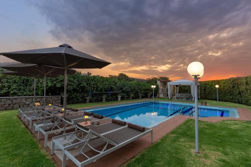 a swimming pool with chairs and an umbrella at Villa Clio, with Mountain view in Arménoi
