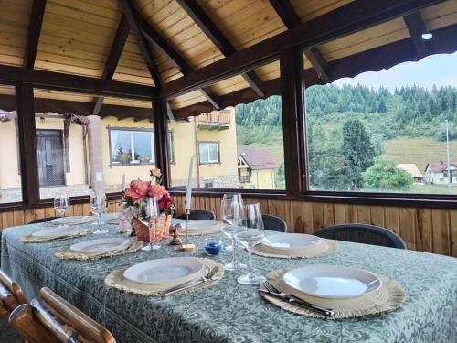 a table with plates and glasses on top of a room at Casa de pe Uliță in Fundata