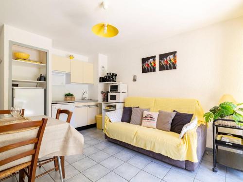 un salon avec un canapé jaune et une cuisine dans l'établissement Appartement T2 avec jardinet, parking et casier à skis, quartier thermal, proche télécabine, 2 étoiles - FR-1-296-171, à Saint-Lary-Soulan