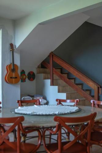 a dining room with a table and chairs and a guitar at Sossego Homestay - Chapada dos Guimarães in Chapada dos Guimarães