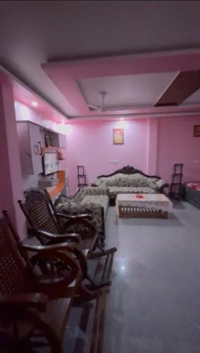 a bedroom with pink walls and a bed and chairs at Rishi home stay in Bhauli