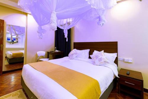a bedroom with a large bed with purple walls at Marrkson Suites Hotel in Nairobi