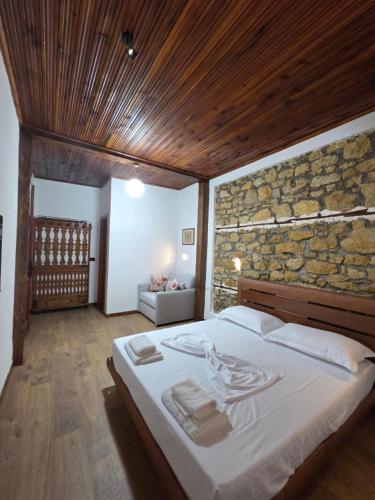 a bedroom with a large bed with a stone wall at Antique House Muradie in Vlorë