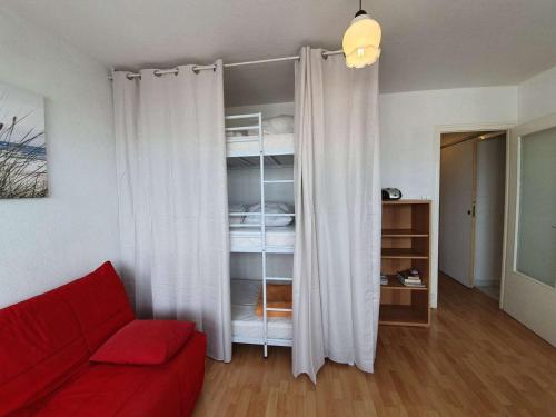 un salon avec un canapé rouge et une chambre dans l'établissement Studio cosy à 50m de la plage - 4 couchages, loggia vue mer, lave-linge, ménage inclus - FR-1-224C-418, à Saint-Hilaire-de-Riez