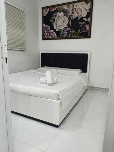 a white bed in a room with a picture on the wall at Muong Thanh Oceanfront Retreat apartment in Nha Trang