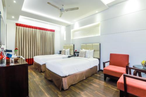 a hotel room with two beds and a chair at Hotel Grand Godwin - Free Airport Pick-Up in New Delhi