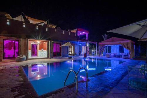a swimming pool at night with purple lights at 5-Bedroom Villa Guesthouse with Heated Pool in Tillouna