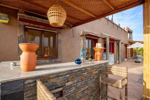 an outdoor bar with chairs and vases on a patio at 5-Bedroom Villa Guesthouse with Heated Pool in Tillouna