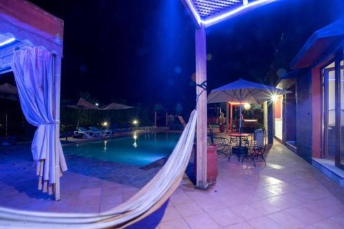 a swimming pool with a hammock next to a house at 5-Bedroom Villa Guesthouse with Heated Pool in Tillouna