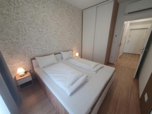 a large white bed with white sheets and pillows at SzemesBay Apartment in Balatonszemes