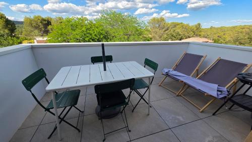 une table blanche et des chaises sur un balcon dans l'établissement L'Appartement Panorama des Pins, à Lambesc