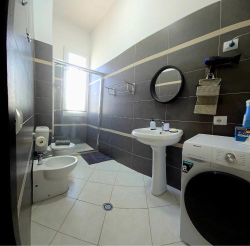 a bathroom with a sink and a toilet and a mirror at Bindi Studio Apartment in Draç