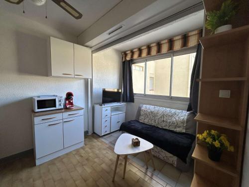 Il comprend une petite cuisine avec un canapé et un four micro-ondes. dans l'établissement Appartement 2 pièces à Narbonne Plage, proche plage, parking - FR-1-229B-108, à Narbonne