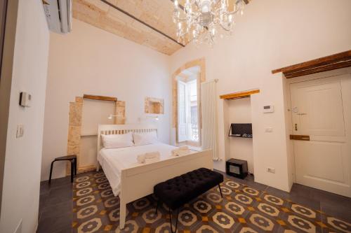 a bedroom with a white bed and a chandelier at La Pupa coi baffi - Edificio Storico in Centro in Conversano