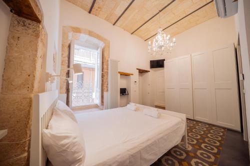 a bedroom with a white bed and a chandelier at La Pupa coi baffi - Edificio Storico in Centro in Conversano